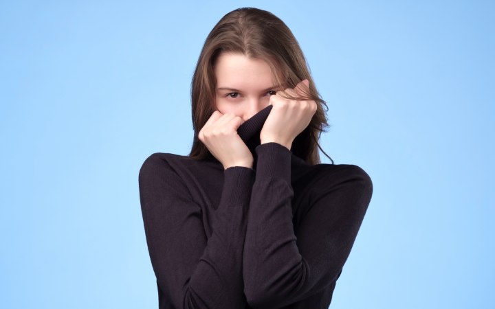 Girl who is hiding her face behind her turtleneck